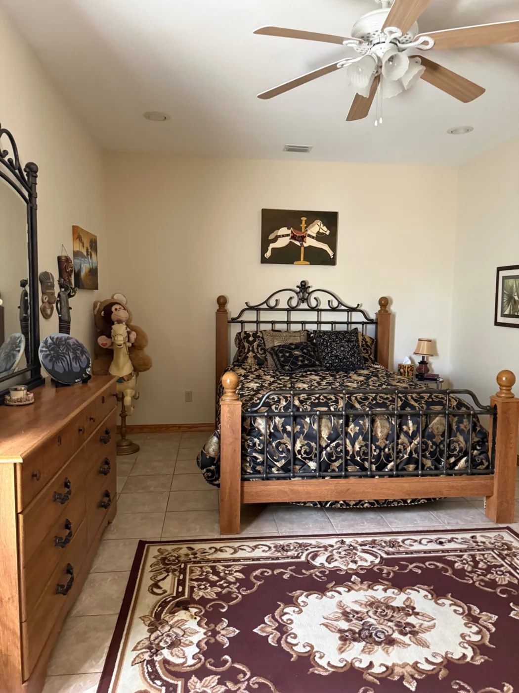 Bedroom with a made bed, wood furniture and tile floors