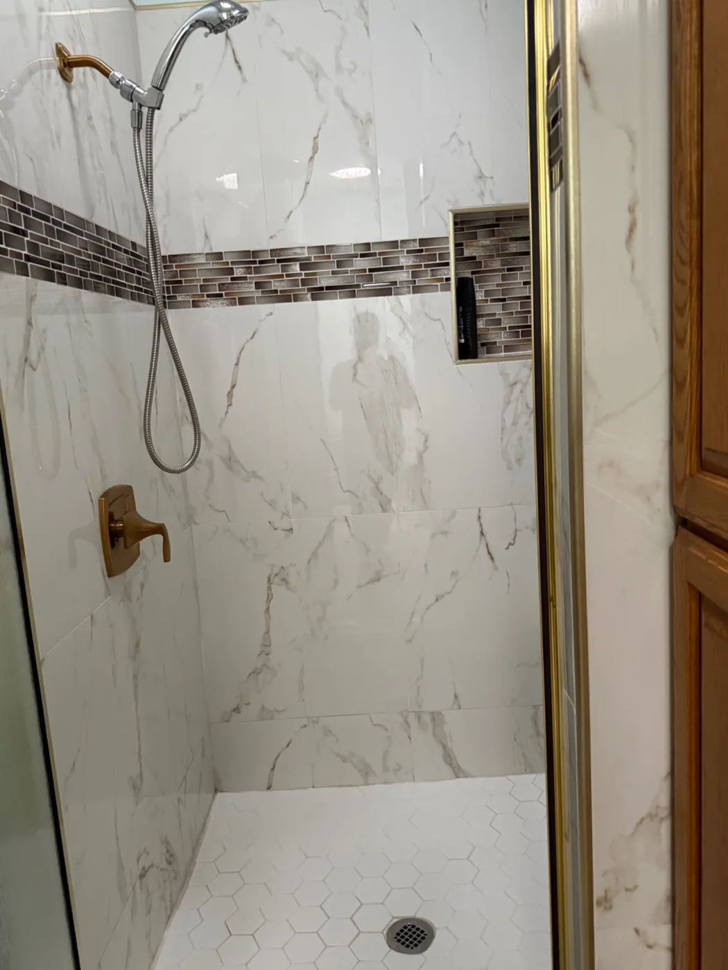 Walk-in shower with tile walls, glass door and hexagonal floor tile